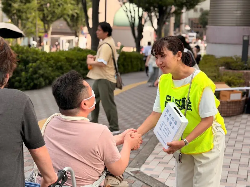 募金をいただいた車いすの男性と握手を交わす澤田議員