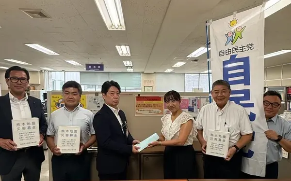集めた募金を担当者へ手渡しする議員一同
